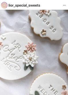 some decorated cookies are laying on a white table cloth with words and flowers in the middle