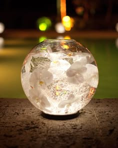 a glass ball with flowers inside sitting on the ground