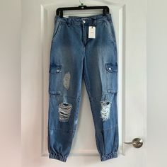 Nwt Forever 21 Denim Jogger Cargo Pants Size 28 Color Blue Fitted Waist/ Relaxed Hips Distressed Look 100% Cotton Machine Washable A Pair Of Stonewashed Jeans Featuring A Distressed Design, Ankle Cut, Jogger Hem, Cargo Pockets With A Snap-Button Flap Closures, Four Pocket Construction, And A Zip Fly With A Button Closure. Smoke Free Home High Waist Medium Wash Bottoms From Forever 21, Trendy Straight Leg Bottoms By Forever 21, Forever 21 Straight Leg Bottoms With Pockets, Trendy Forever 21 Straight Leg Bottoms, Trendy Forever 21 Bottoms With Pockets, Ripped Denim Utility Bottoms, Fall Forever 21 Straight Leg Bottoms, Forever 21 High Waist Casual Jeans, Casual Ripped Denim Cargo Pants