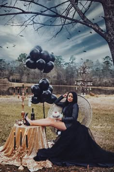 a woman sitting in a chair with black balloons floating over her and holding a drink