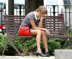 a woman is sitting on a bench with her hand in her purse and looking down