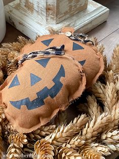 a pumpkin pillow sitting on top of a pile of pine cones