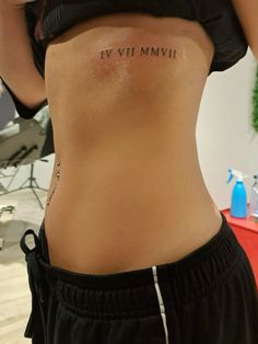 the back of a woman's stomach with roman numerals written on it