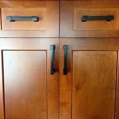 a close up of a wooden cabinet with black handles