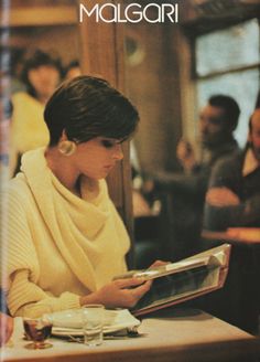 a woman sitting at a table reading a book