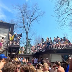 a group of people standing on top of a roof in front of a building with lots of trees