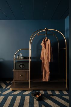 a coat rack and shoes in a blue room with striped rugs on the floor