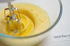 a yellow liquid in a glass bowl with a whisk attachment