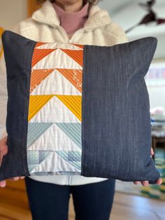 a woman holding up a pillow made out of denims and fabric with an arrow design on it