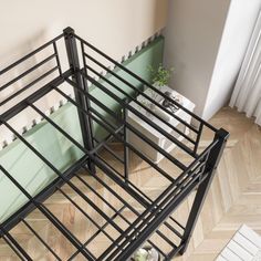 a metal bed frame sitting on top of a hard wood floor next to a window