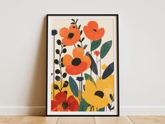 an orange and yellow floral print hangs on the wall next to a wooden floor in front of a white wall