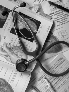 a stethoscope laying on top of medical papers with pictures of the human body