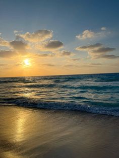 the sun is setting over the ocean with waves coming in