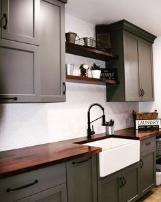 a kitchen with gray cabinets and wooden counter tops, including a white farmhouse sink in the center