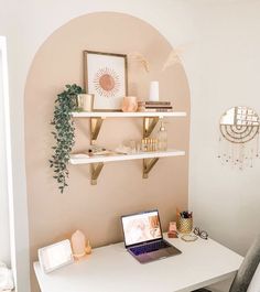 a laptop computer sitting on top of a white desk next to a wall mounted shelf