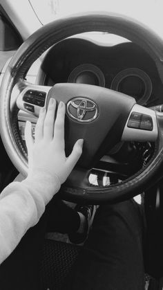 a person driving a car with their hand on the steering wheel and hands on the dashboard