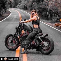 a woman sitting on top of a motorcycle in the middle of an empty road with trees and bushes behind her