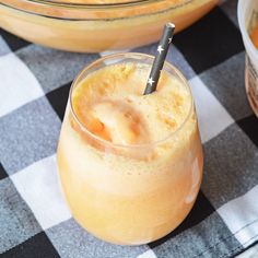 an orange drink in a glass with a black and white checkered table cloth next to it