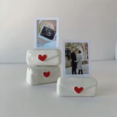 two white frames with red hearts are sitting on a table next to an empty photo