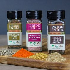 three bottles of spice sit on a cutting board next to other spices and seasonings