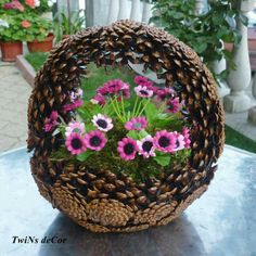 a basket filled with lots of flowers on top of a metal table next to potted plants