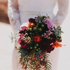 a bride holding a bouquet of flowers and greenery on her wedding day in the sun