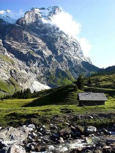 a small cabin in the middle of a mountain valley