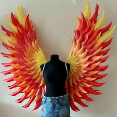 a mannequin is standing next to a display of colorful wings on a wall