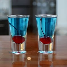 two glasses with cherries in them sitting on a table