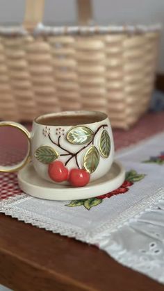 a cup and saucer sitting on top of a wooden table next to a basket