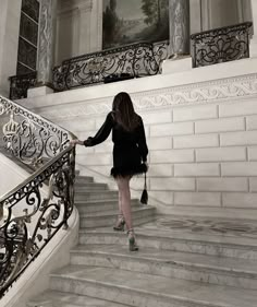 a woman is walking up the stairs in a building