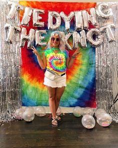 a woman standing in front of a tie dye backdrop with balloons and the words bedding the king on it