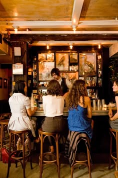 several people sitting at a bar with stools