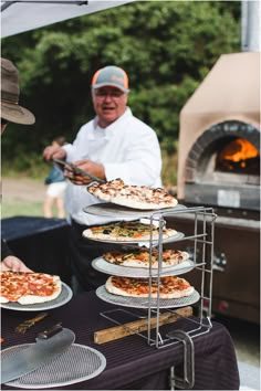 several pizzas being served on plates in front of an outdoor oven