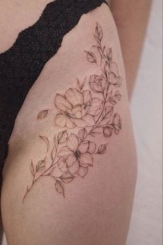 a close up of a woman's thigh with flowers tattoo on her side,