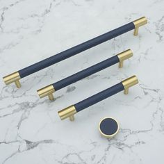 three black and gold handles on a marble counter