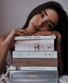 a woman leaning on top of a stack of books