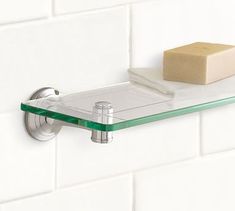 a glass shelf on the wall above a soap bar