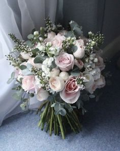 a bouquet of pink roses and greenery sits on the floor next to a window