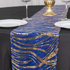 a blue table runner with gold sequins on it, along with white plates