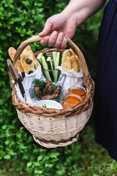 a person holding a wicker basket filled with food