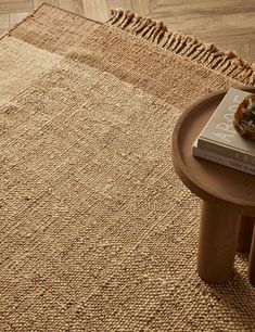 a table with a book on top of it next to a rug and wooden floor