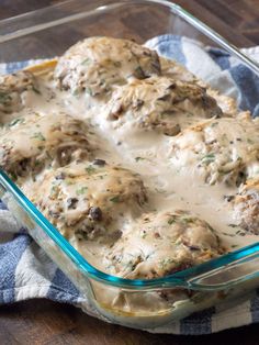 a casserole dish with meatballs covered in gravy on a blue and white towel