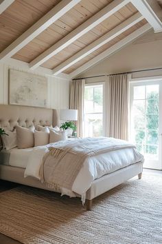 a large bed sitting in the middle of a bedroom next to a window with curtains