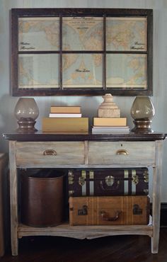 an old world map hangs on the wall above a table with suitcases and books