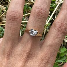 a woman's hand with a heart shaped diamond ring on top of her finger