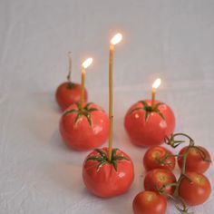 tomatoes and candles are arranged on a white surface