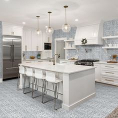 a kitchen with white cabinets and marble counter tops, stainless steel appliances and stools