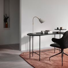 a black table with a lamp and some books on it next to a white wall