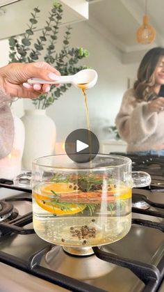 a woman is pouring tea into a bowl on the stove